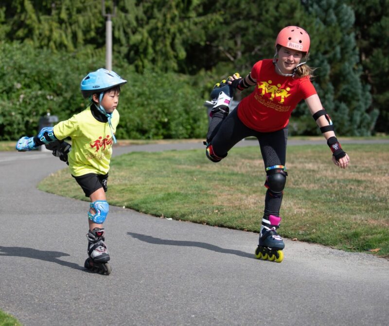 Two kids rollerblading on a path.